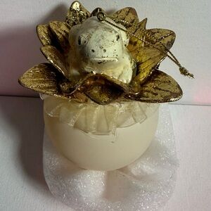 Frog ornament in cream and gold . Details of gold petals frog lays on